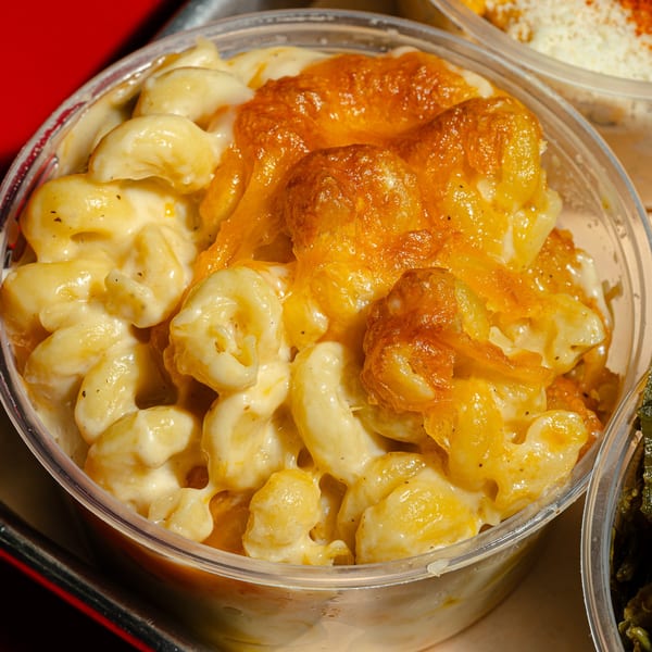 Sanders BBQ Supply Co.'s baked mac and cheese with a golden-brown crust in a clear plastic container.