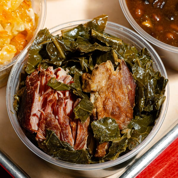 Close-up of Sanders BBQ collard greens with pulled pork in a clear plastic container.
